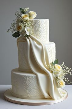 a three tiered white wedding cake with flowers on top