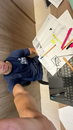 a young man sitting at a desk with his laptop and papers on the table next to him