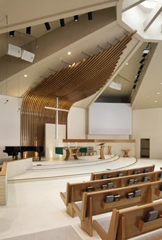 an empty church with rows of pews in the foreground and a projector screen on the far wall