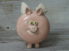 a ceramic pig figurine with green eyes and wings on it's head