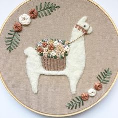 a white llama with flowers and leaves on it's back in a embroidery hoop