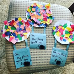 some paper plates with different colored pieces of paper on them sitting on top of a chair