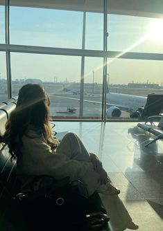 a woman is sitting in an airport waiting for her plane to take them off the runway