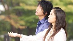 two people standing next to each other with trees in the background