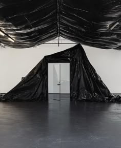 an empty room with black tarp covering the walls and door in front of it