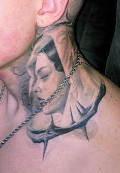 a man with a tattoo on his neck and chest is looking at the camera while wearing a chain around his neck