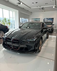 a black sports car is on display in a showroom with other cars behind it
