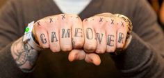 tattooed hands with the word game over written on them