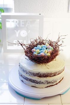 a cake with white frosting and chocolate eggs in the nest on top of it
