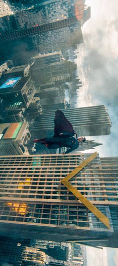 a man standing on top of a tall building in the middle of a large city