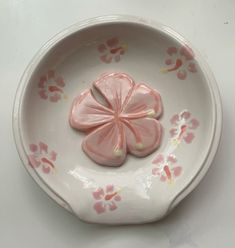 a white bowl with pink flowers on the side and one flower is in the middle
