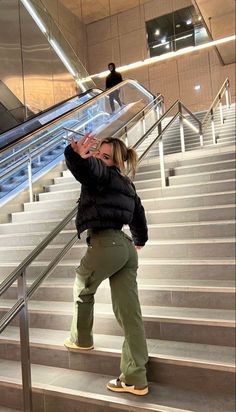a woman taking a selfie while standing on the stairs in front of an escalator