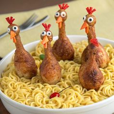 four chicken legs are placed on top of noodles in a bowl with eyes drawn on them