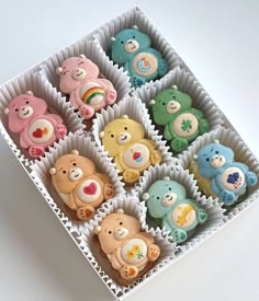 there are many different colored teddy bears in the cupcakes box on the table