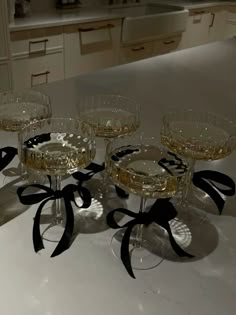 four wine glasses sitting on top of a counter with black ribbon around the rims