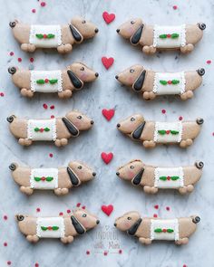 some cookies shaped like dachshund dogs on a marble table with red hearts