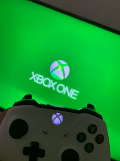 a close up of a video game controller in front of a xbox one logo on a wall