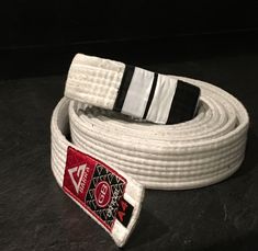 a white belt with black and red stripes on the end is sitting on a table