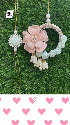 a pink flower is hanging from a string on the grass with hearts in the background