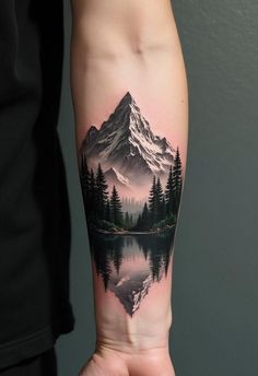 a person with a tattoo on their arm holding a small lake in front of a mountain