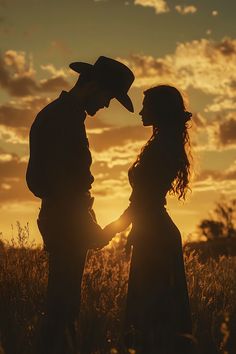a man and woman are standing in the grass at sunset with their arms around each other
