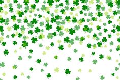 many green shamrocks are flying in the air