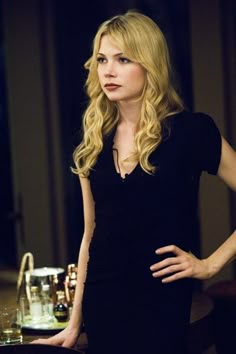 a woman in a black dress standing next to a table