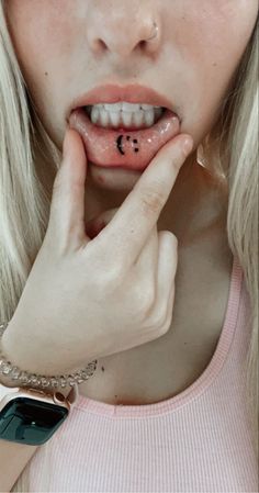 a woman with white hair and piercings holding her hand up to her face