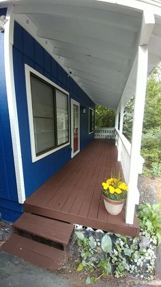 a blue and white house with flower pots on the front porch next to steps that lead up to it