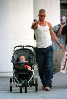a man walking down the street with a baby in a stroller and pointing at something