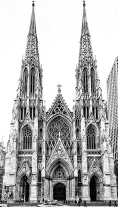 a black and white photo of a cathedral with cars parked in the street below it