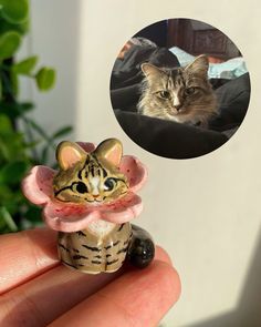 a small cat figurine is sitting on someone's hand with a photo of it