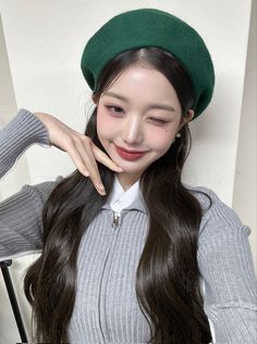 a woman with long hair wearing a green hat