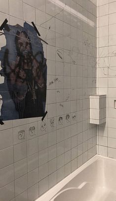 a bathroom with white tiled walls and black graffiti on the wall