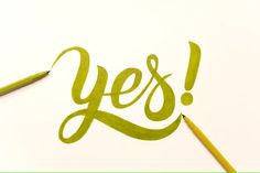 the word yes is drawn with green marker on white paper next to a yellow pencil