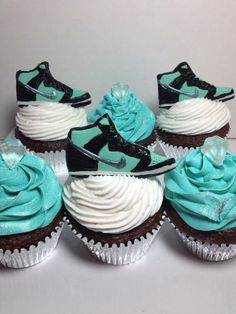 there are many cupcakes with blue frosting and nike shoes on them,
