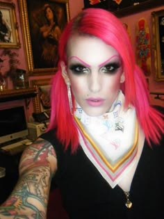 a woman with bright pink hair and black makeup is posing for a photo in her home