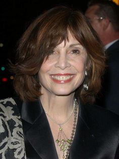 a woman in a black jacket smiling at the camera