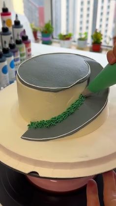 a person is decorating a cake with green icing on the top and bottom