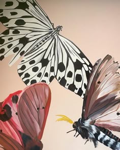 three butterflies flying in the air on a pink and black wallpapered background with polka dots