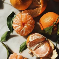 oranges with leaves and peeled ones on a table