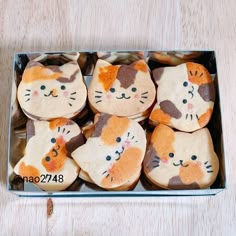 there are many decorated cookies with cats on them in a metal box, one is orange and the other is white
