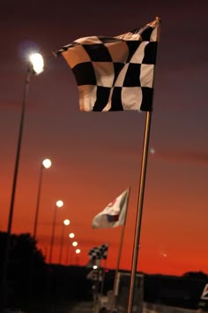 two checkered flags flying in the wind at night