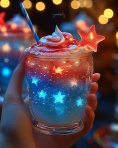a hand holding a cup filled with red, white and blue frosted desserts