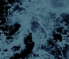 an aerial view of the ocean waves in blue and black colors, taken from above