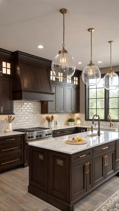 a large kitchen with dark wood cabinets and marble counter tops, lights hanging from the ceiling
