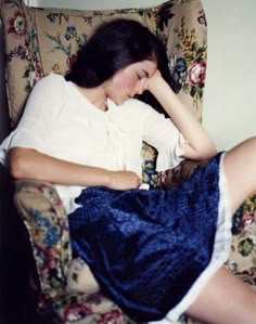 a woman sitting in a chair with her head on her hand