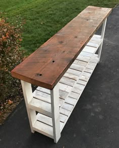 a bench made out of pallet wood sitting on top of a sidewalk next to grass