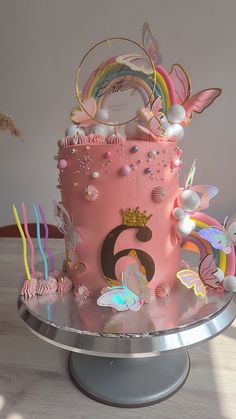 there is a pink cake with butterflies on it and candles in the shape of numbers