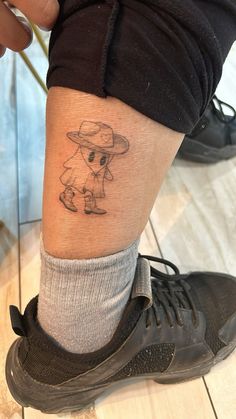 a small tattoo on the leg of a person with a hat and dog in it